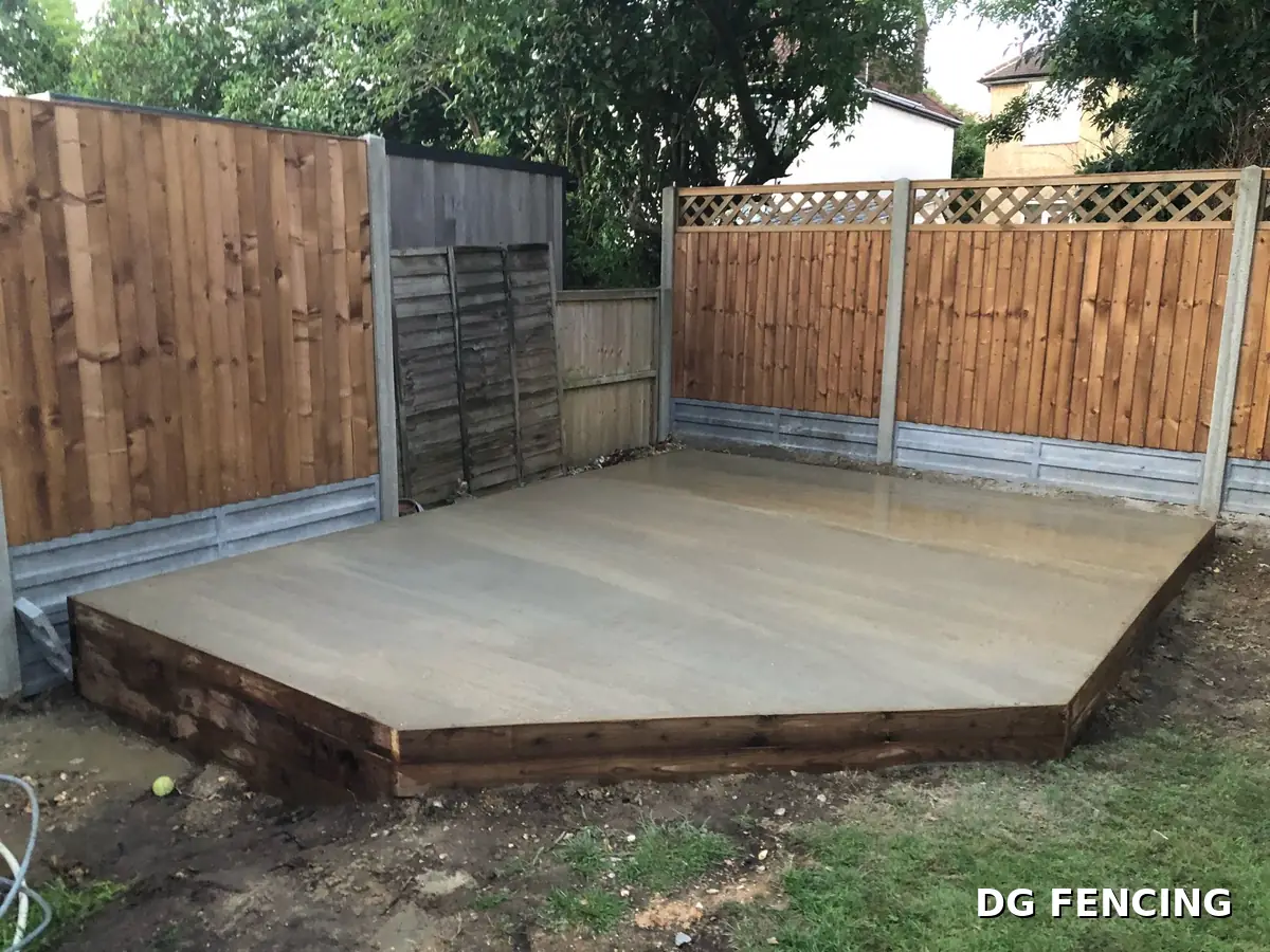Concrete base with timber sleeper edging beside trellis-top fencing